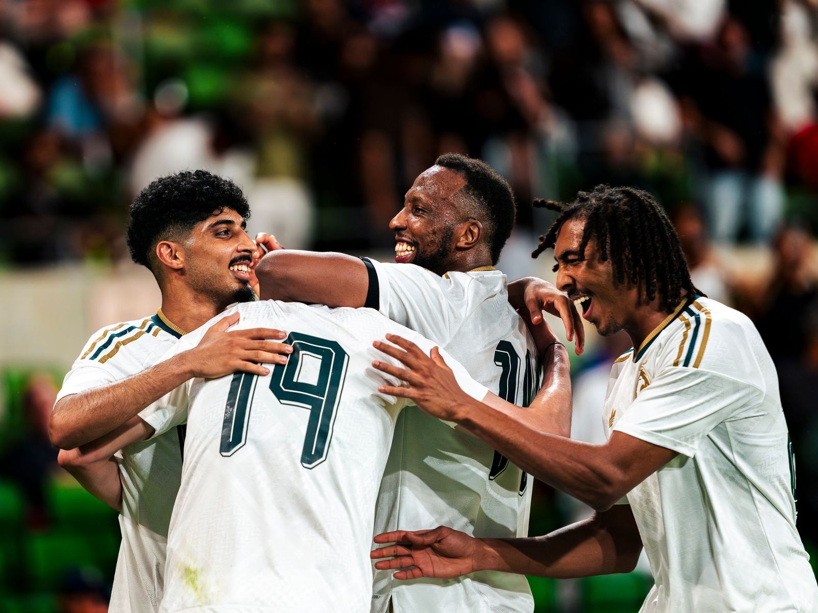 Teammates in white kits embracing after a goal
