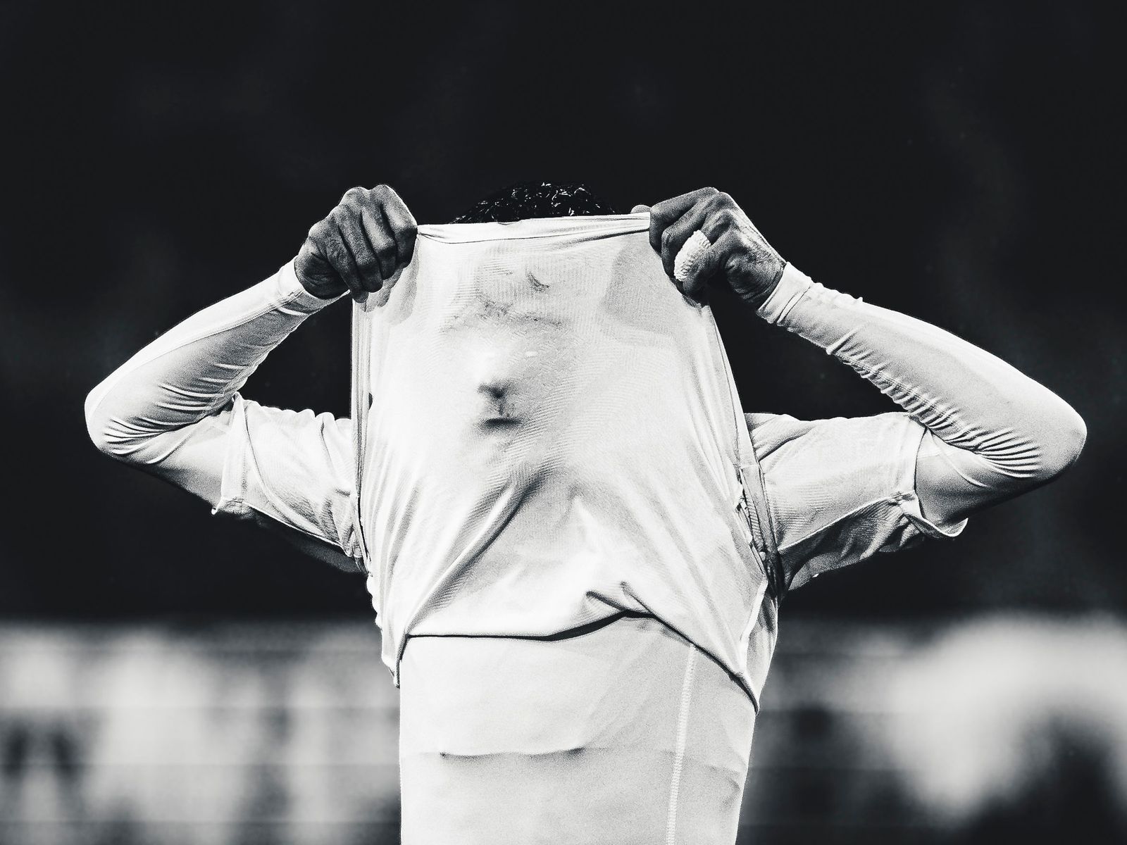 Soccer player pulling his white shirt over his head after a miss