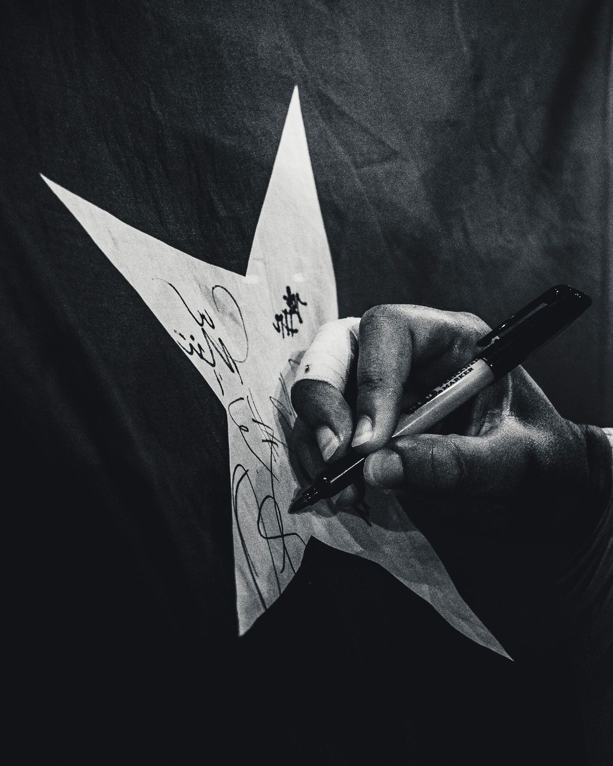 Athlete signing a paper star with a marker, black and white