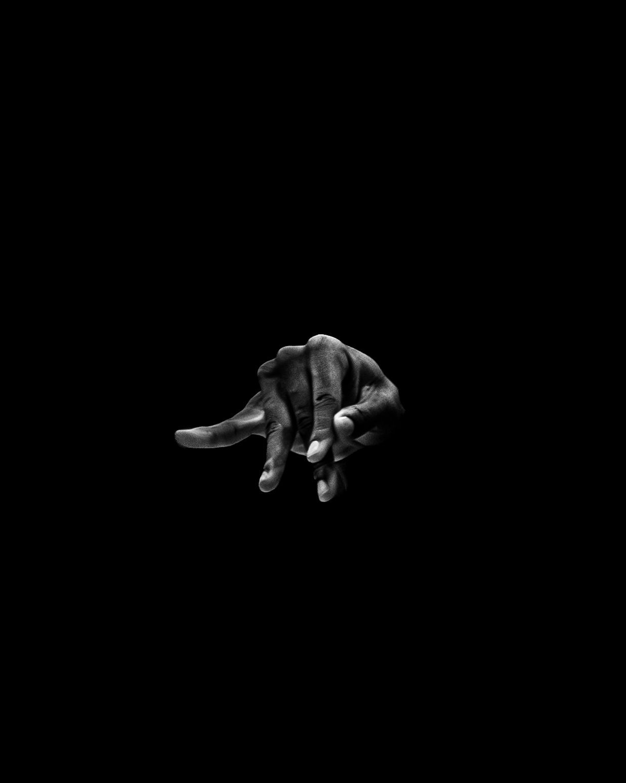 A hand throwing a sign against black