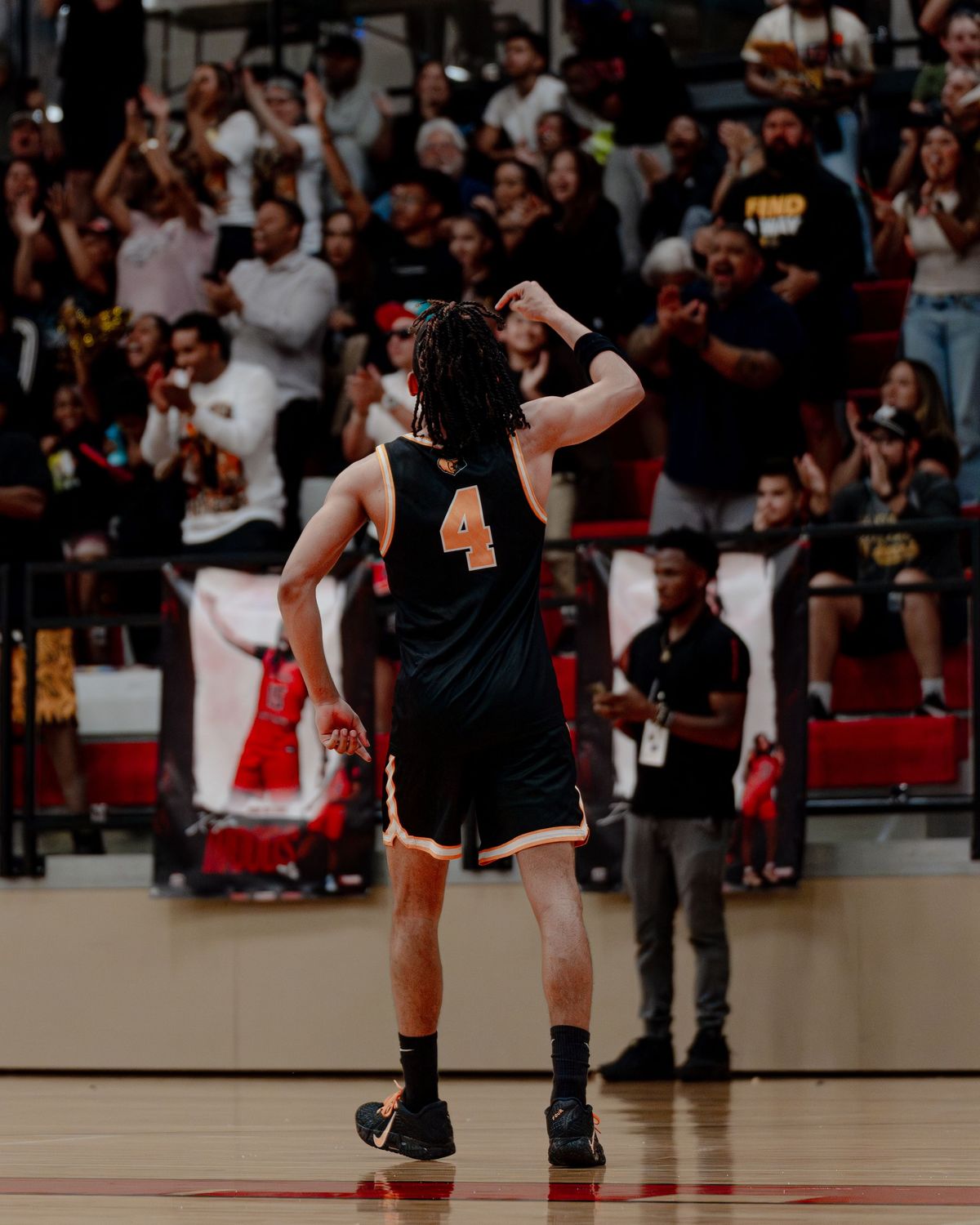 Basketball player in a number 4 jersey walking off court in front of a packed student section