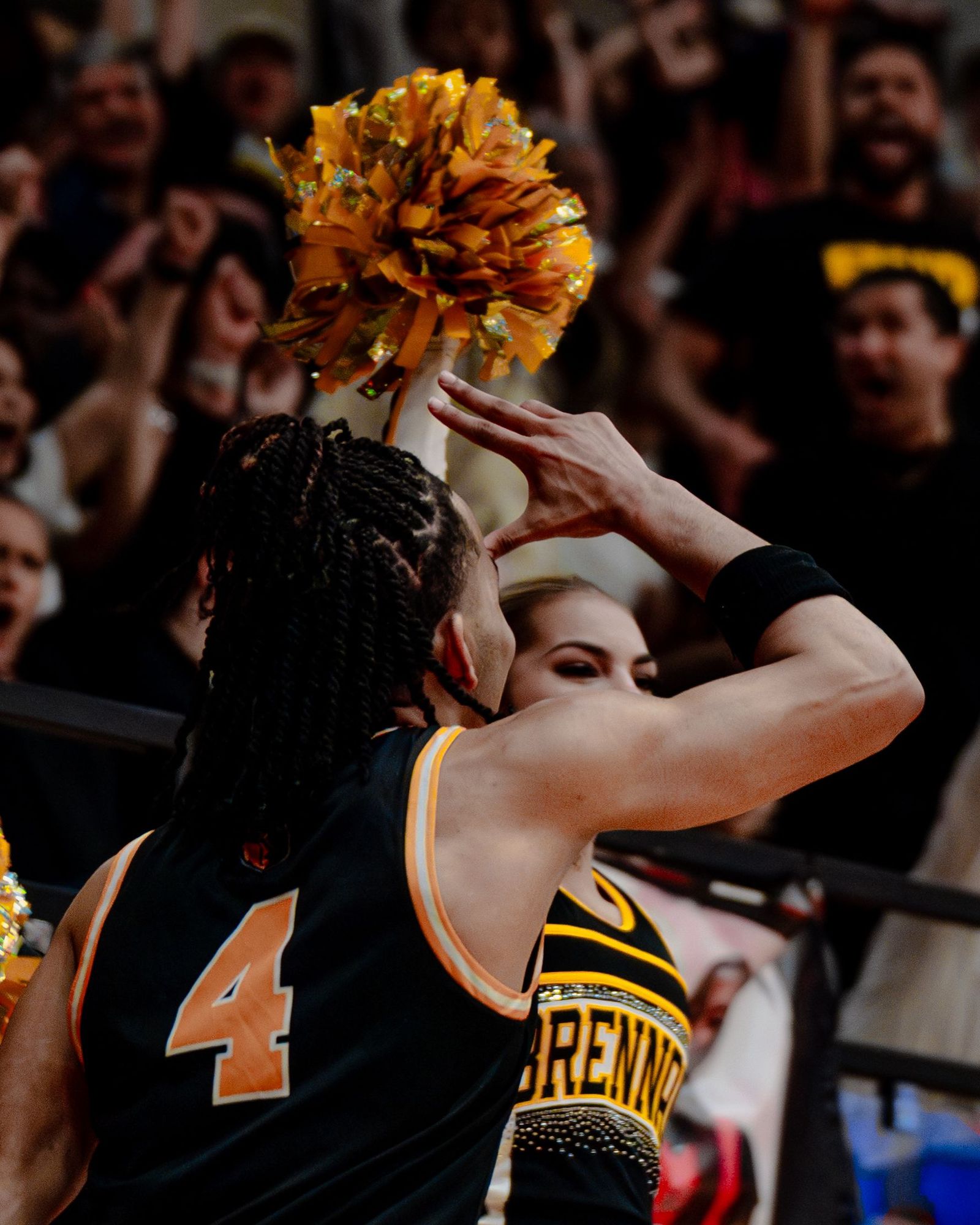 Basketball player facing the student section with pom-poms in the air
