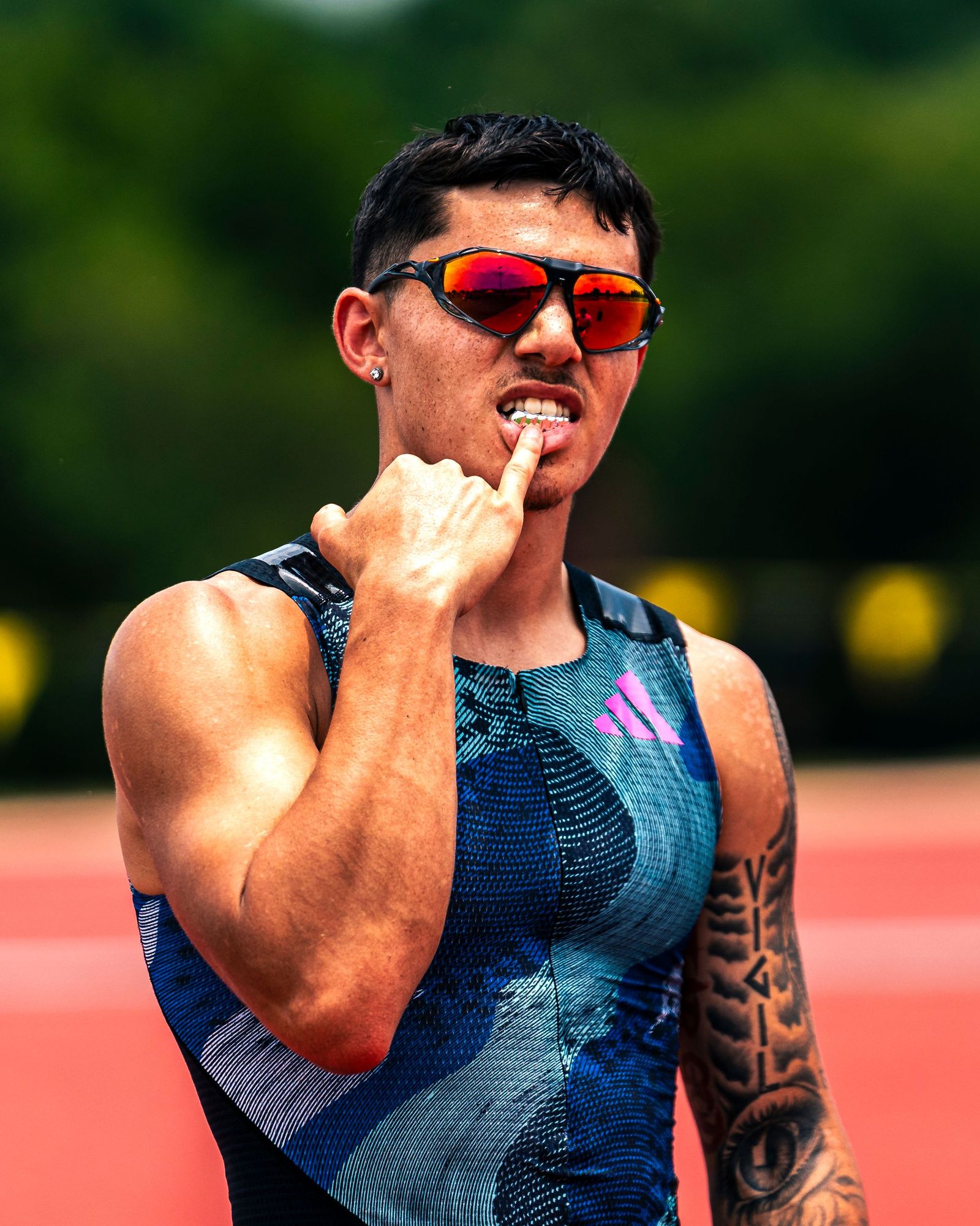 Track athlete in sunglasses biting his finger before a race