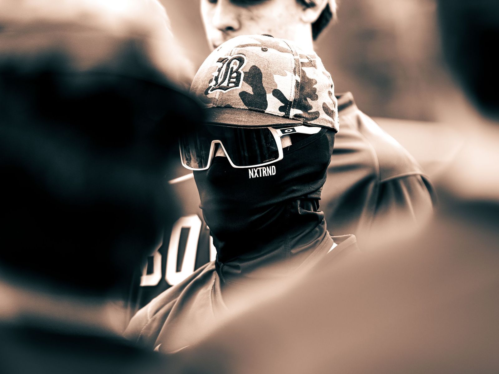Baseball player in a cap and sunglasses staring ahead, sepia
