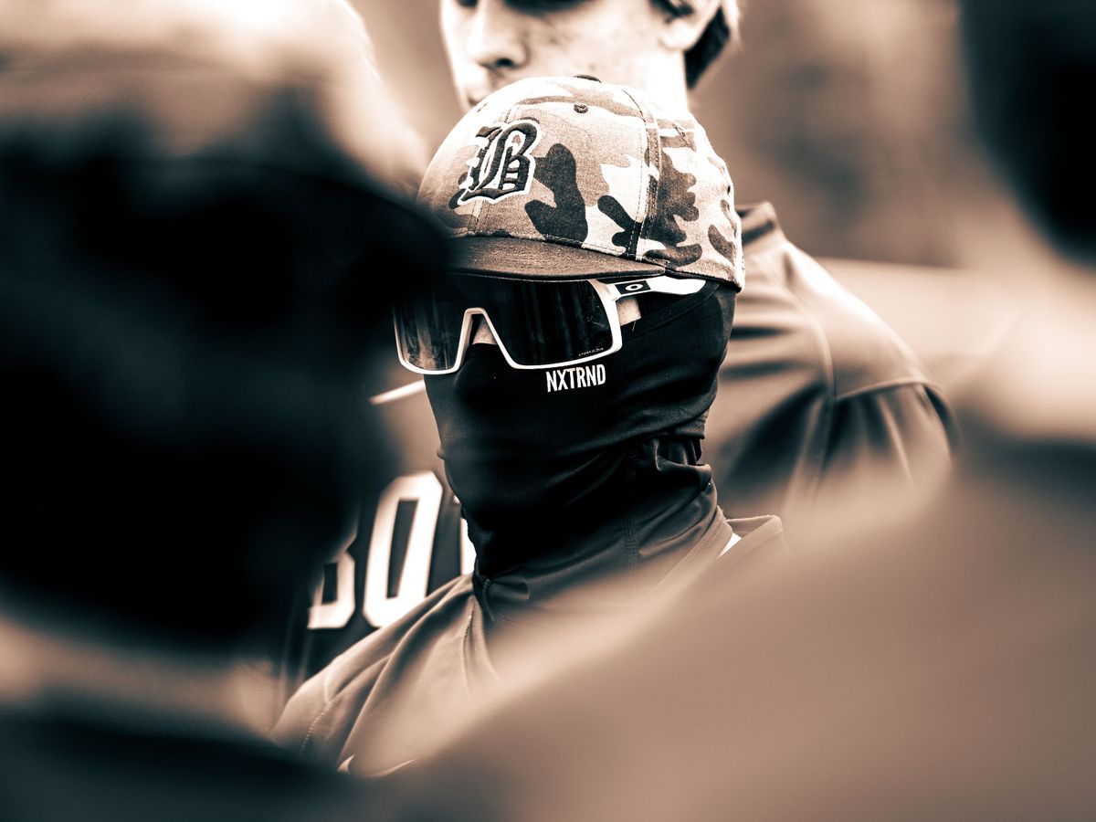 Baseball player in a cap and sunglasses staring ahead, sepia