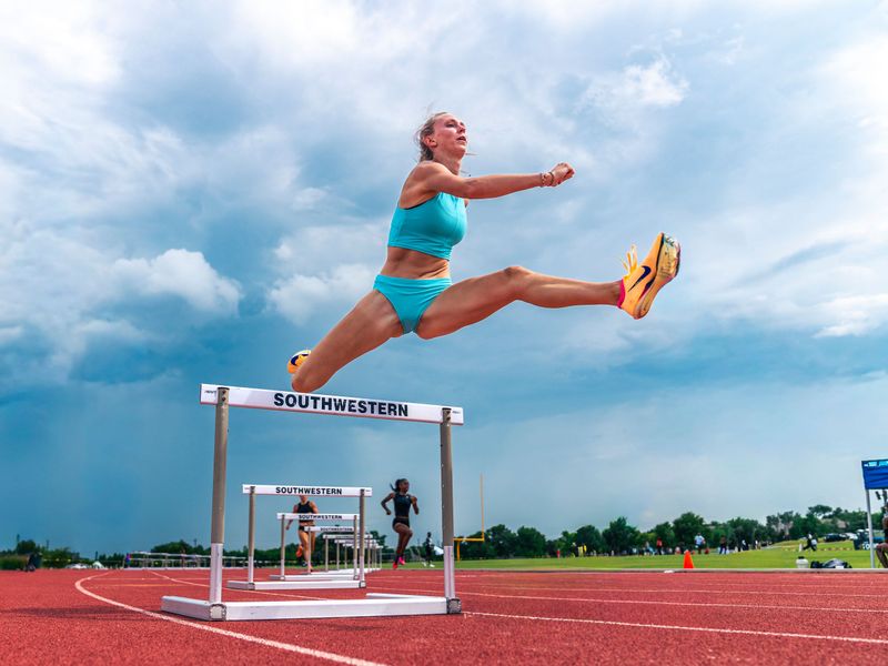 Hurdler clearing a hurdle under a blue sky