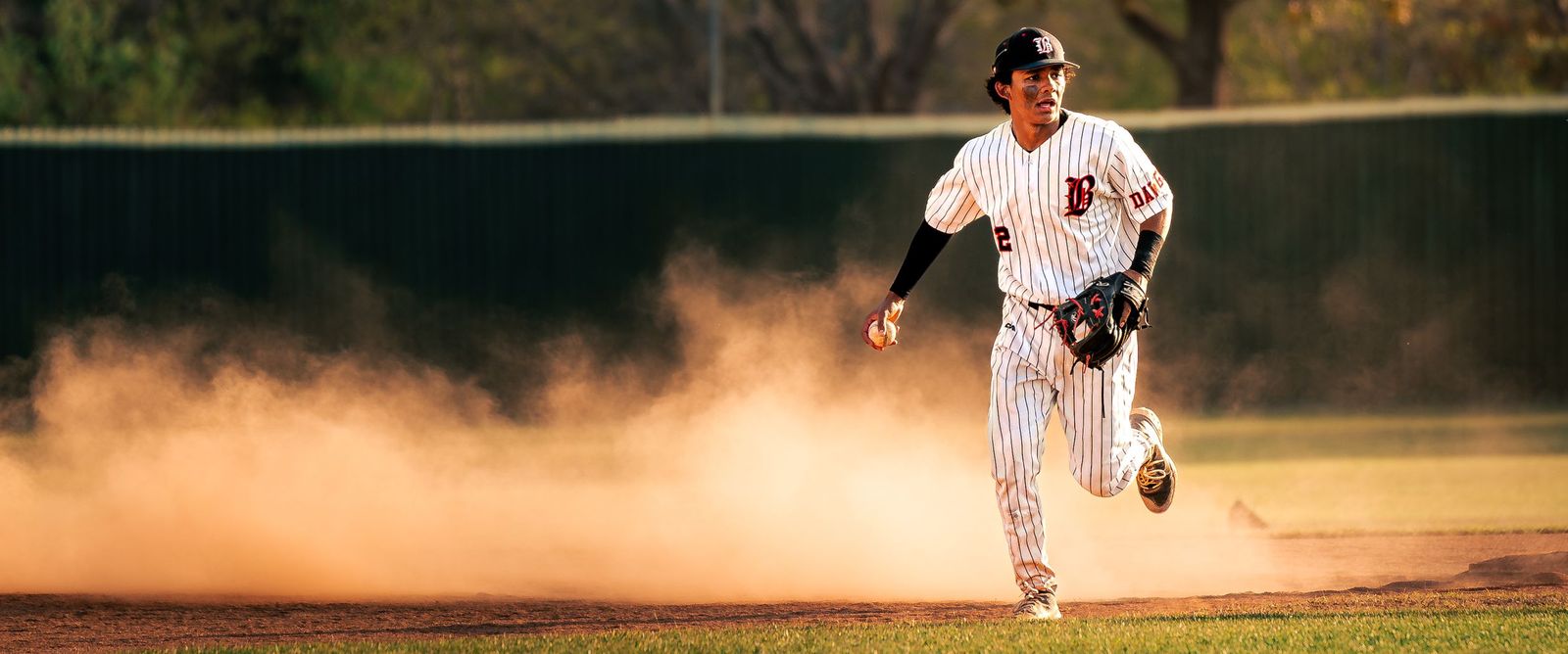 Outfielder sprinting through a cloud of dust