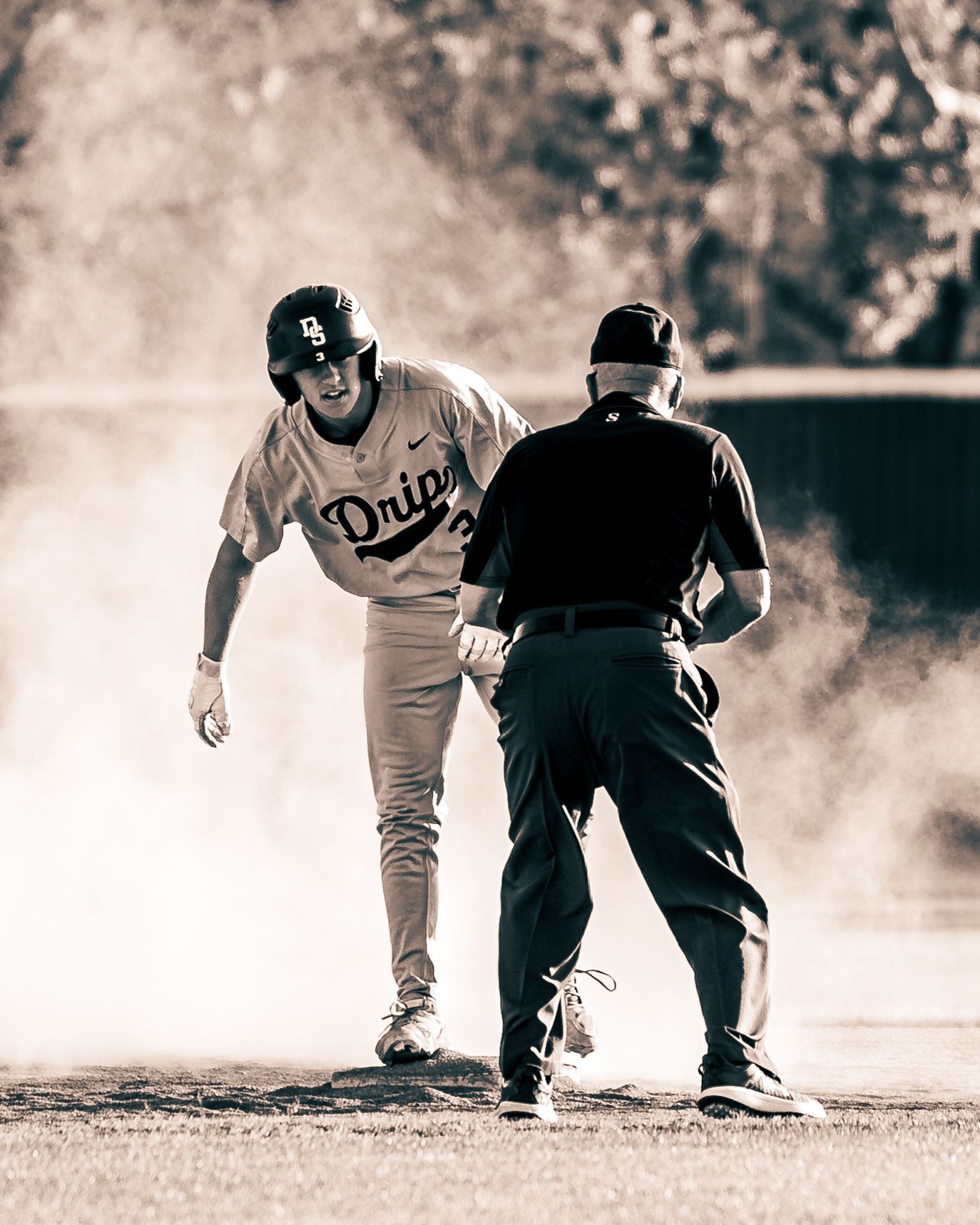 Runner standing on base beside the umpire, black and white