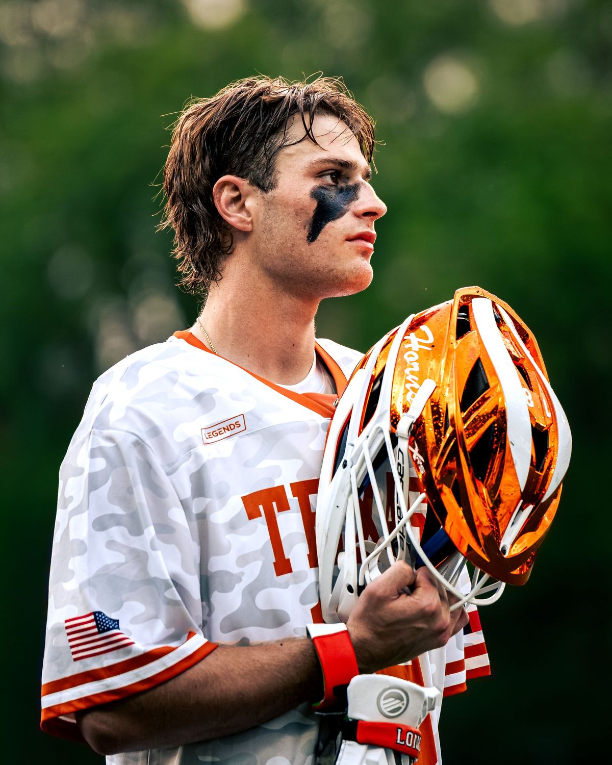Texas lacrosse player holding his helmet in a moment of focus