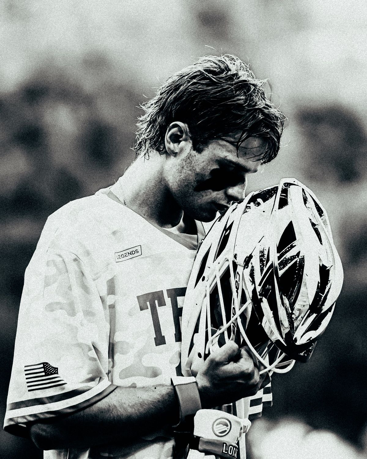 Lacrosse player holding his helmet, black and white