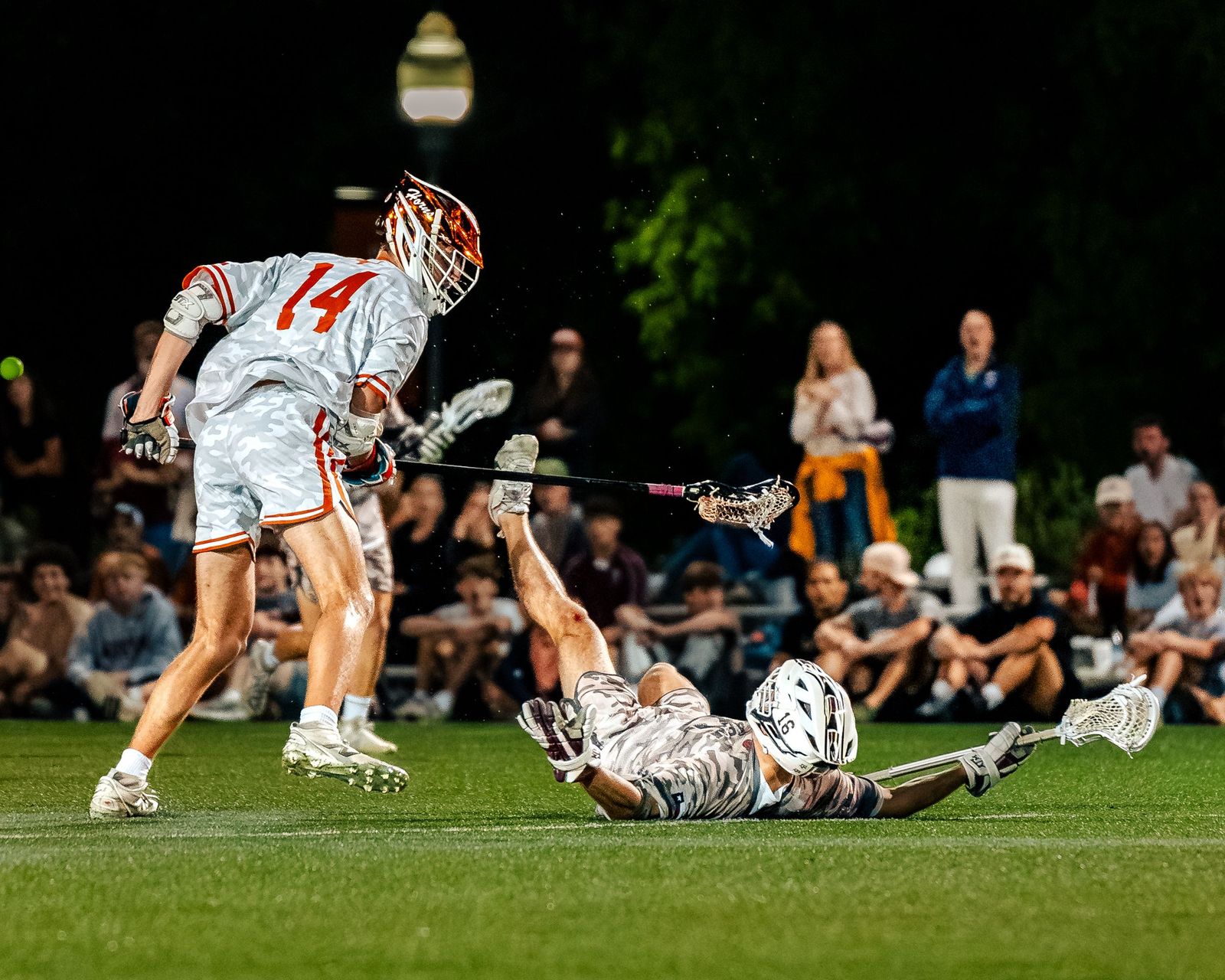 Lacrosse player leaping over a fallen opponent