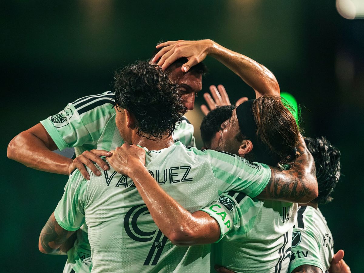 Austin FC players in a group hug after a goal