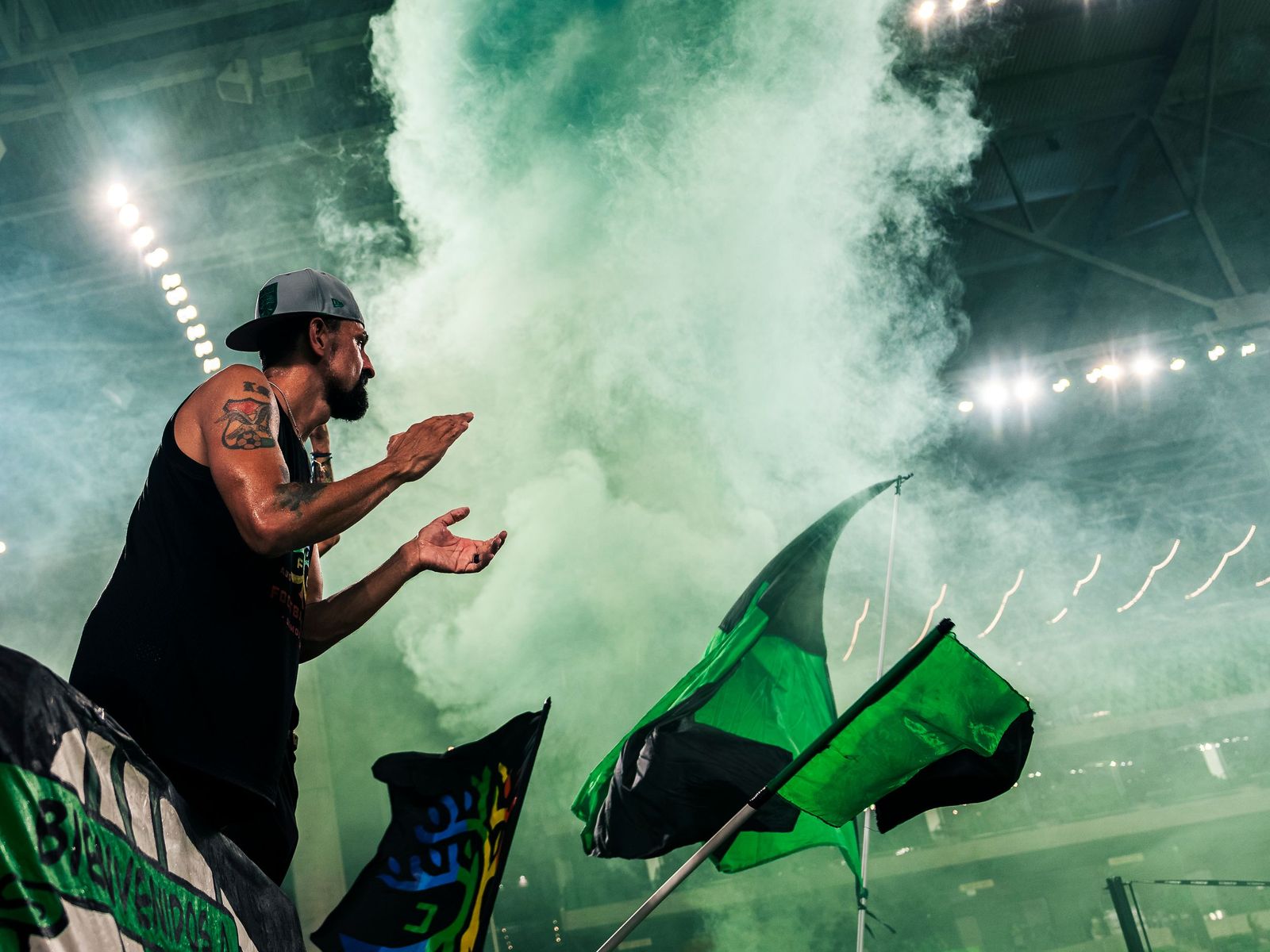 Supporters waving flags through green smoke