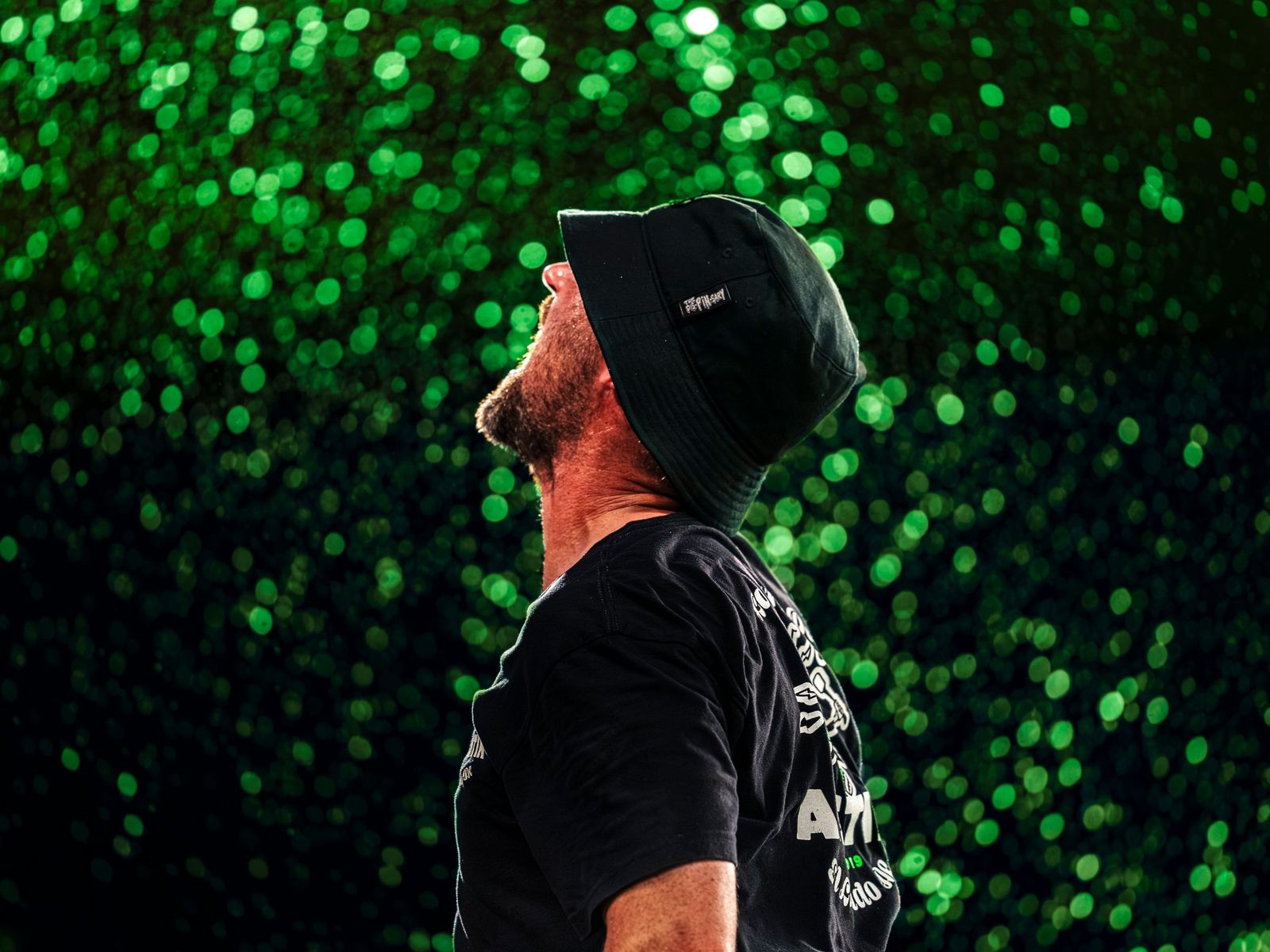 Fan in a bucket hat looking up through falling glitter
