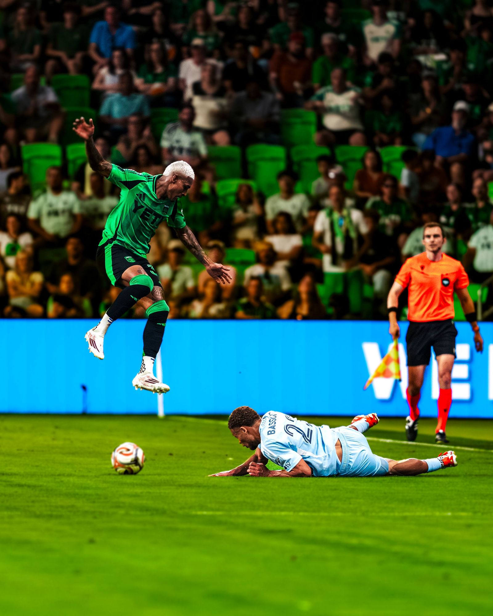 Austin FC player heading the ball as an opponent falls