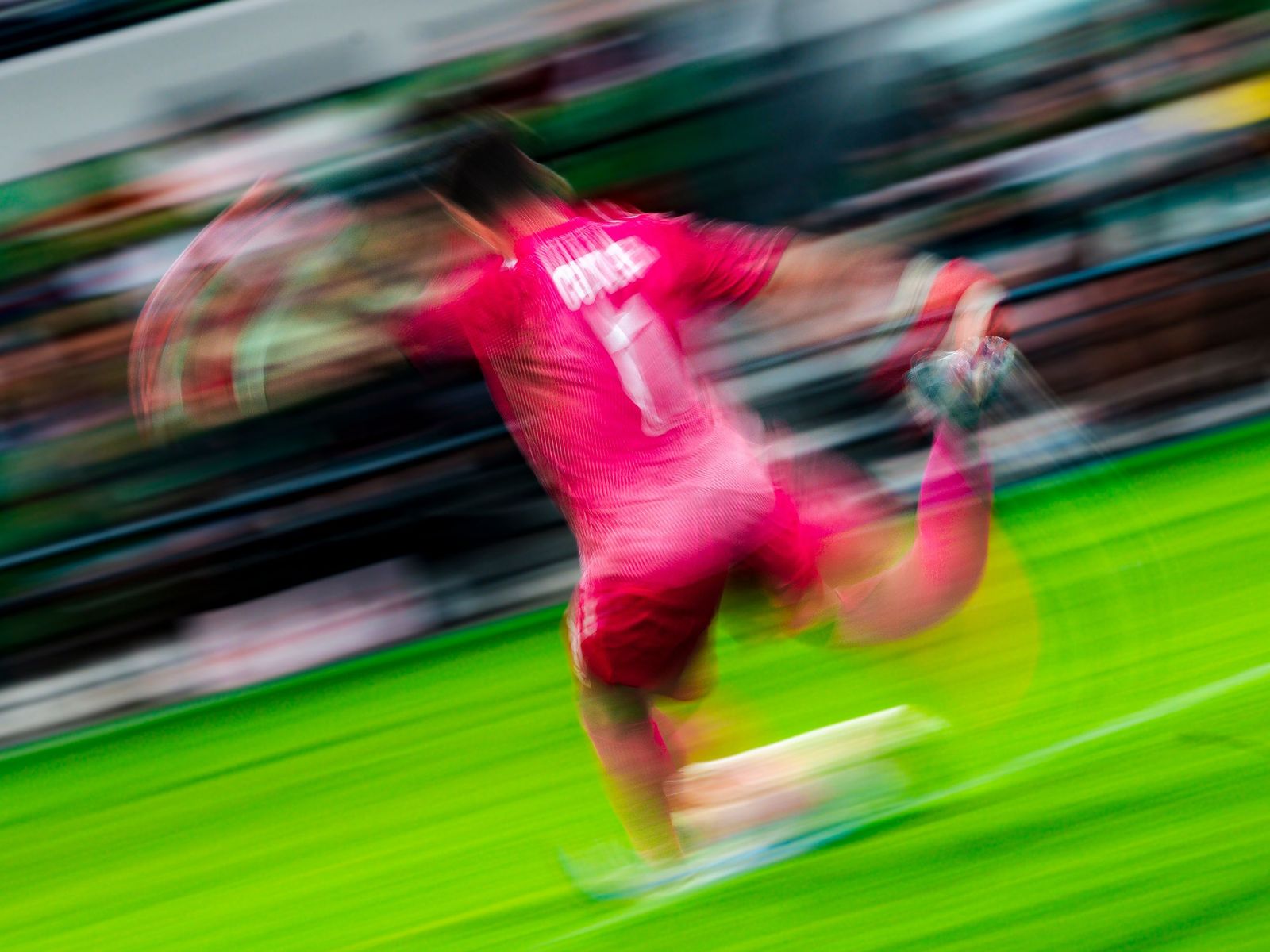 Goalkeeper in pink sprinting across the pitch in a motion blur