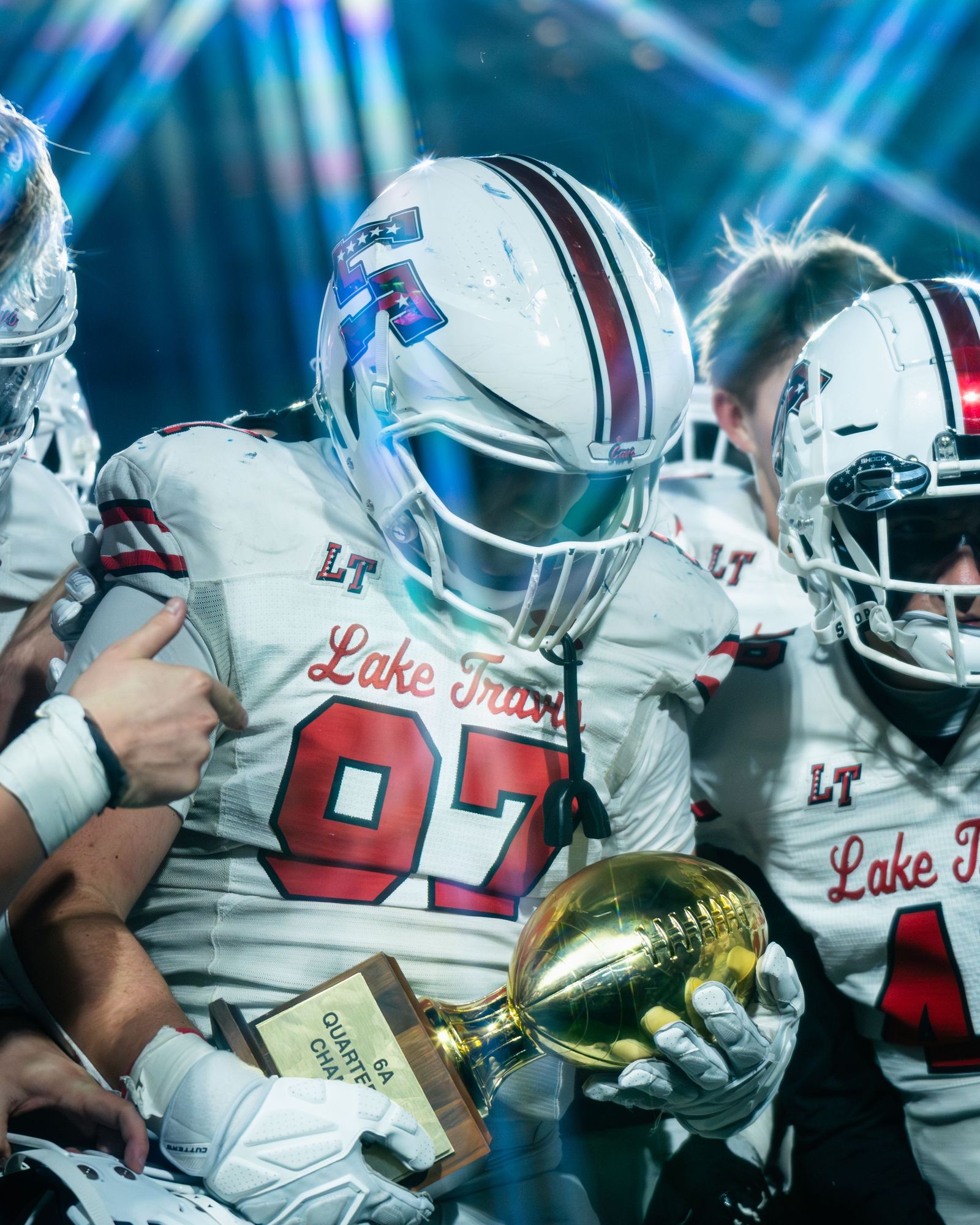 Lake Travis players huddled around a trophy