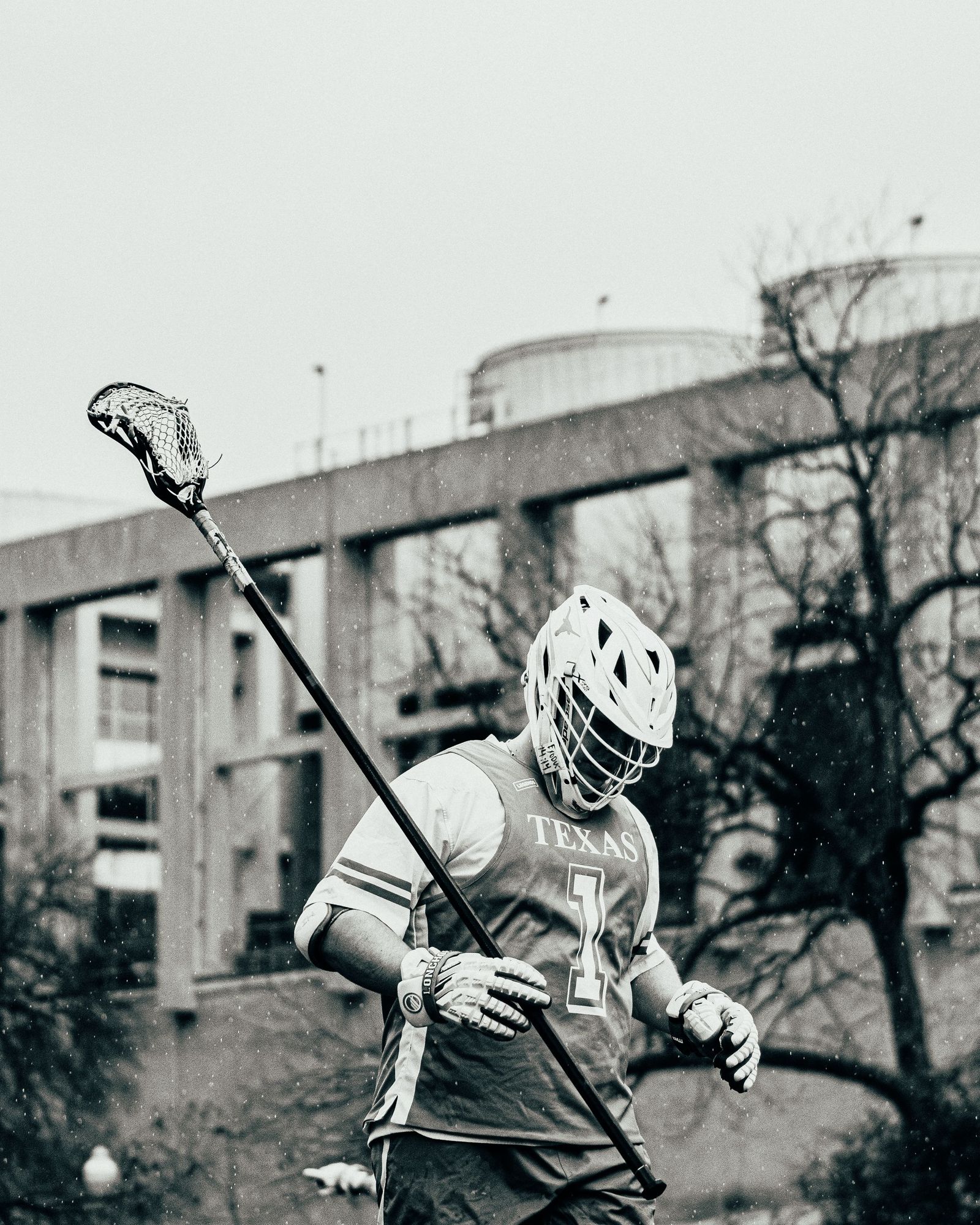 Lacrosse player with stick raised, sepia