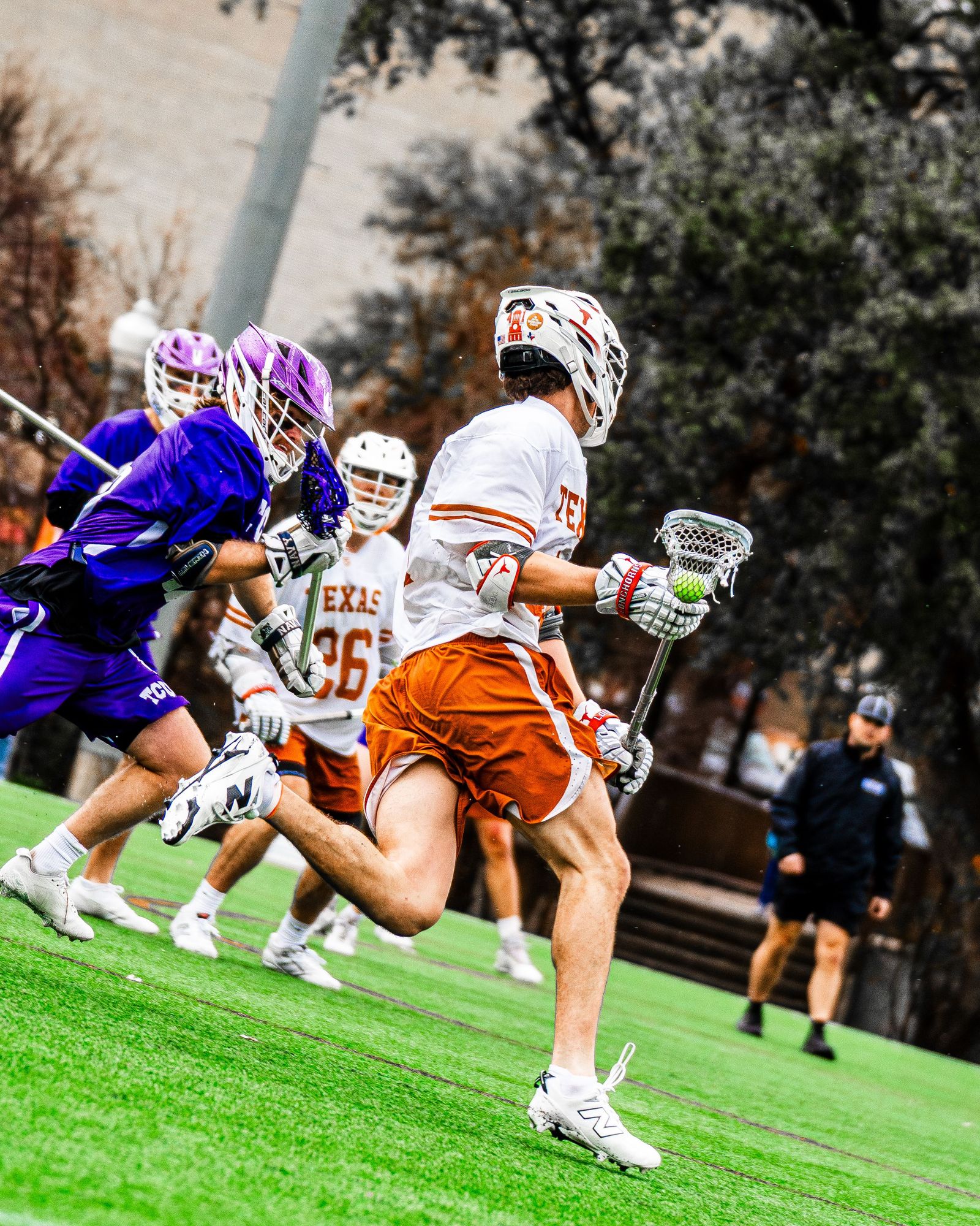 Texas lacrosse player driving past a purple defender
