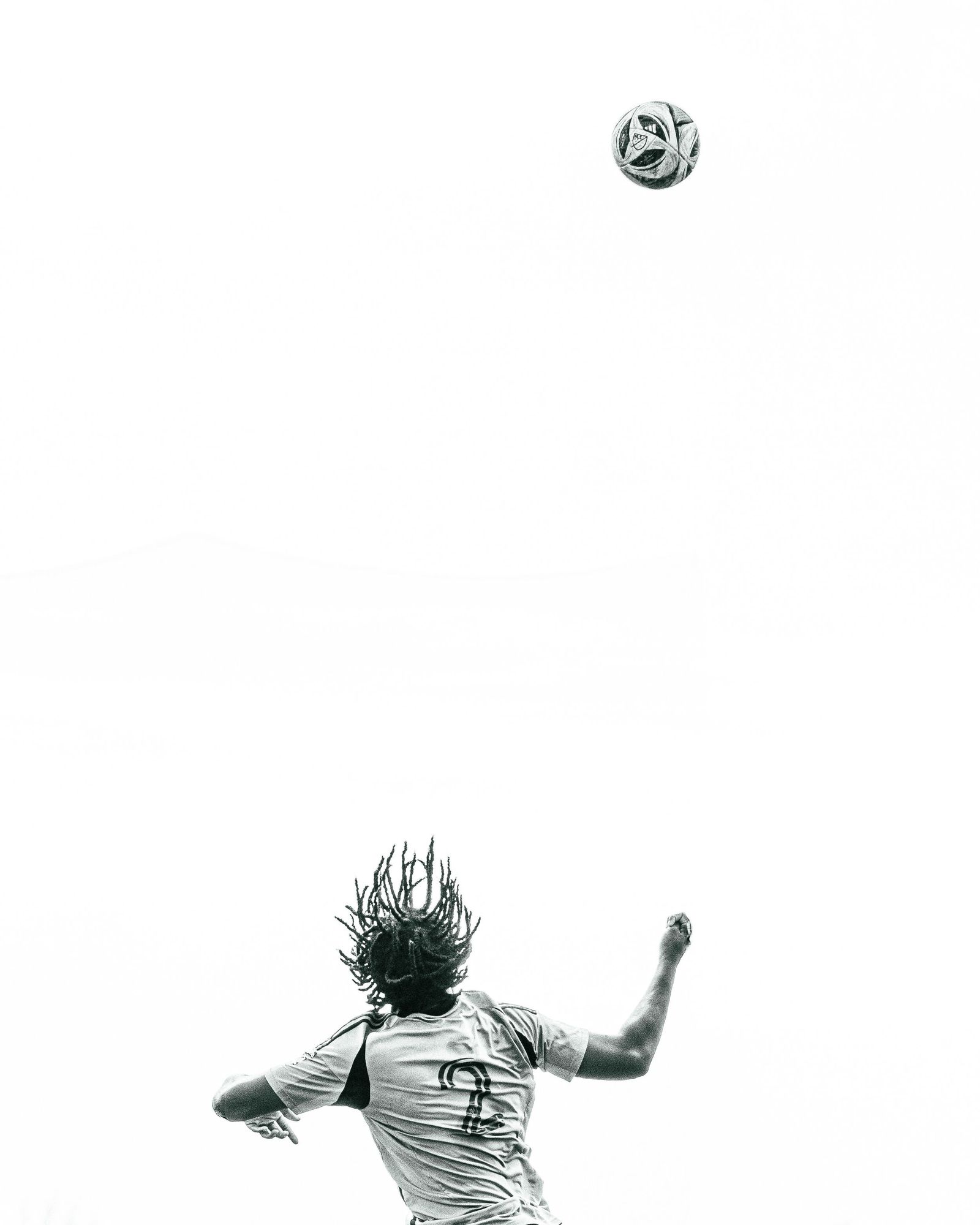 Player tossing a ball high against a white sky