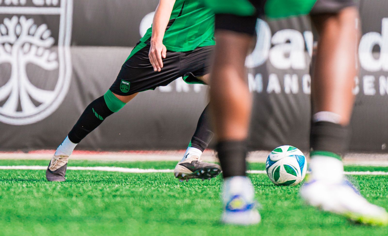 Close-up of feet and a ball on the grass