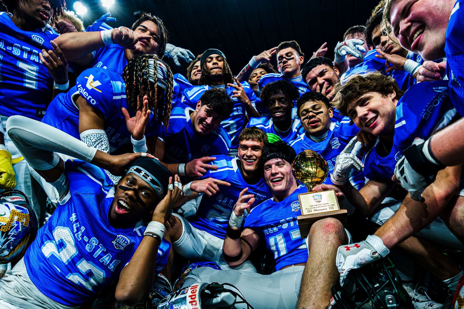 All-star football team piling together for a photo with the trophy