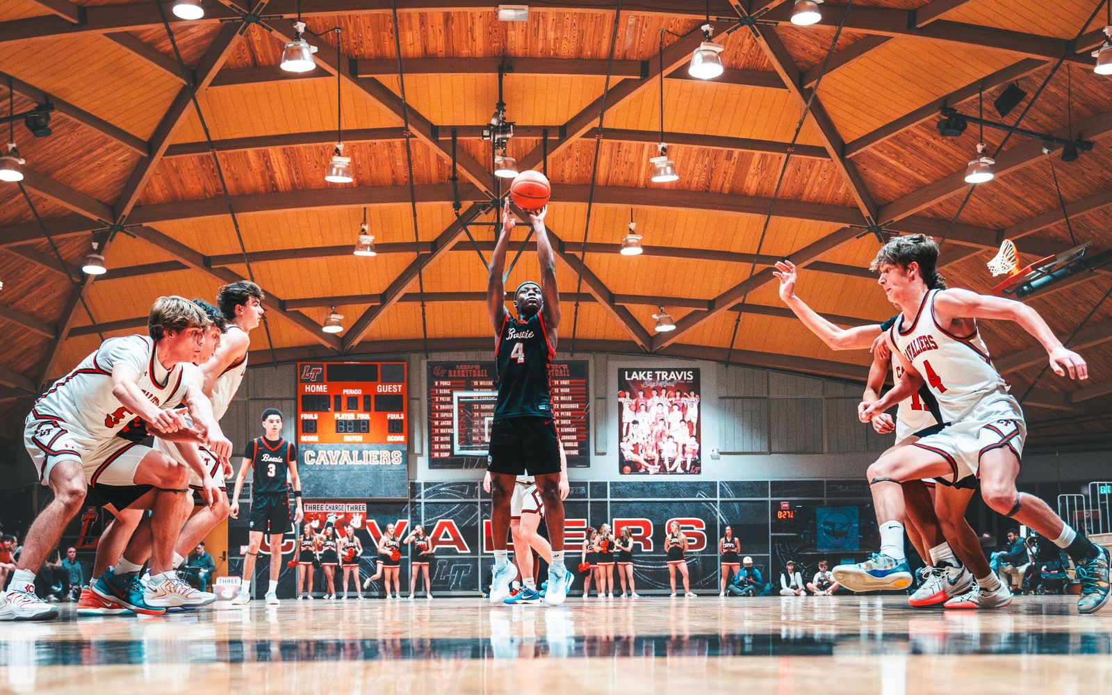 Basketball players fighting for a rebound in a wood-beamed gym