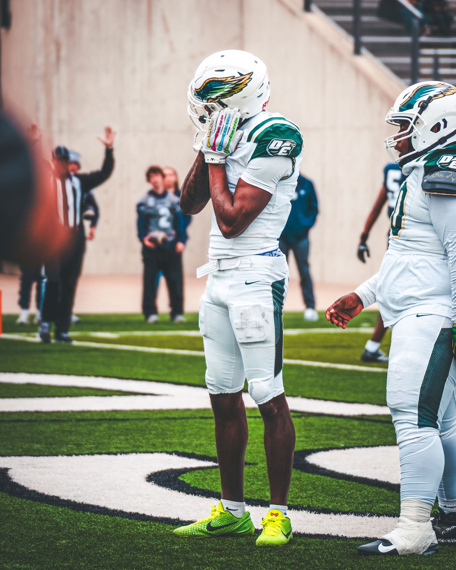 High school football players in white and green uniforms on the field before a snap