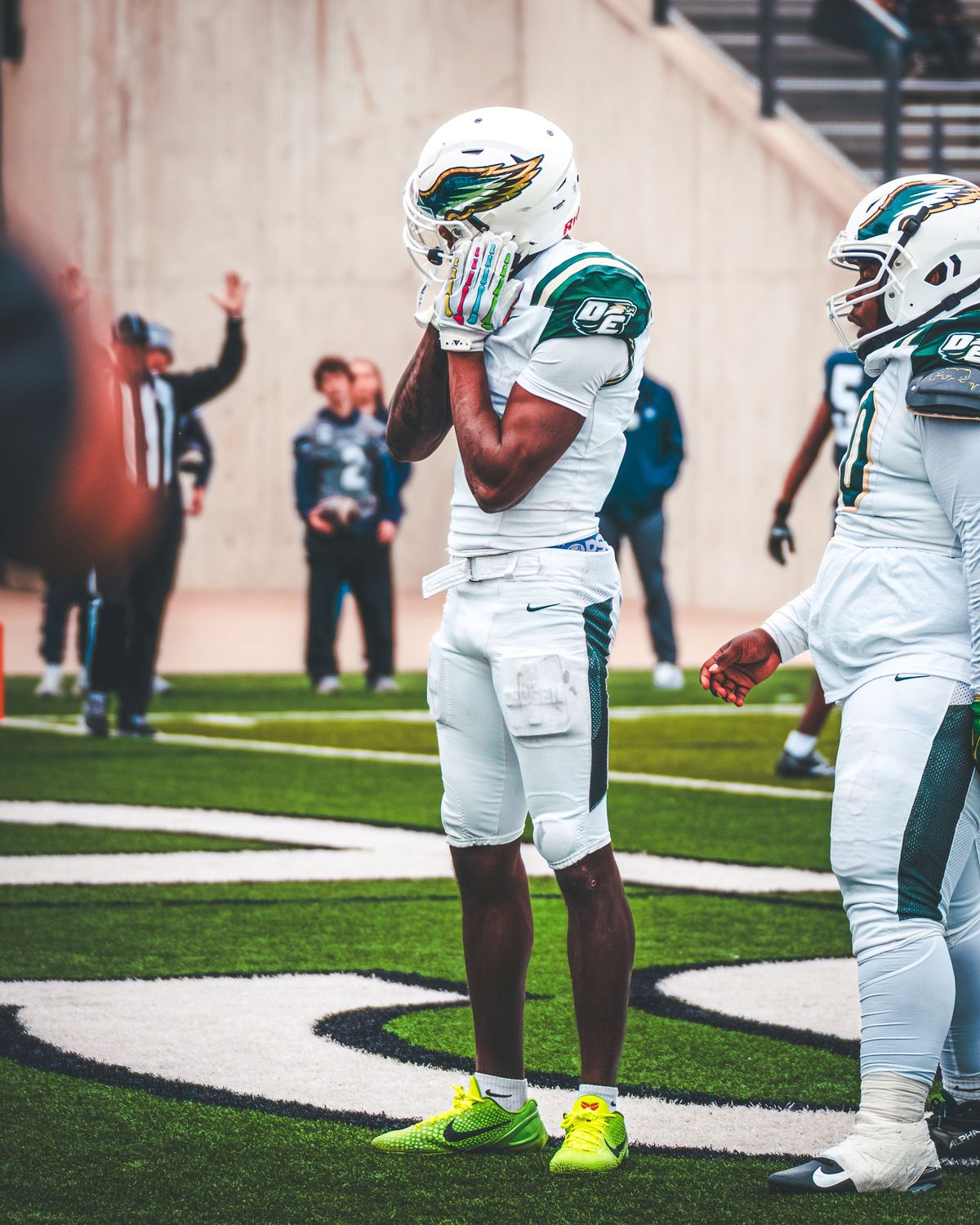 High school football players in white and green uniforms on the field before a snap
