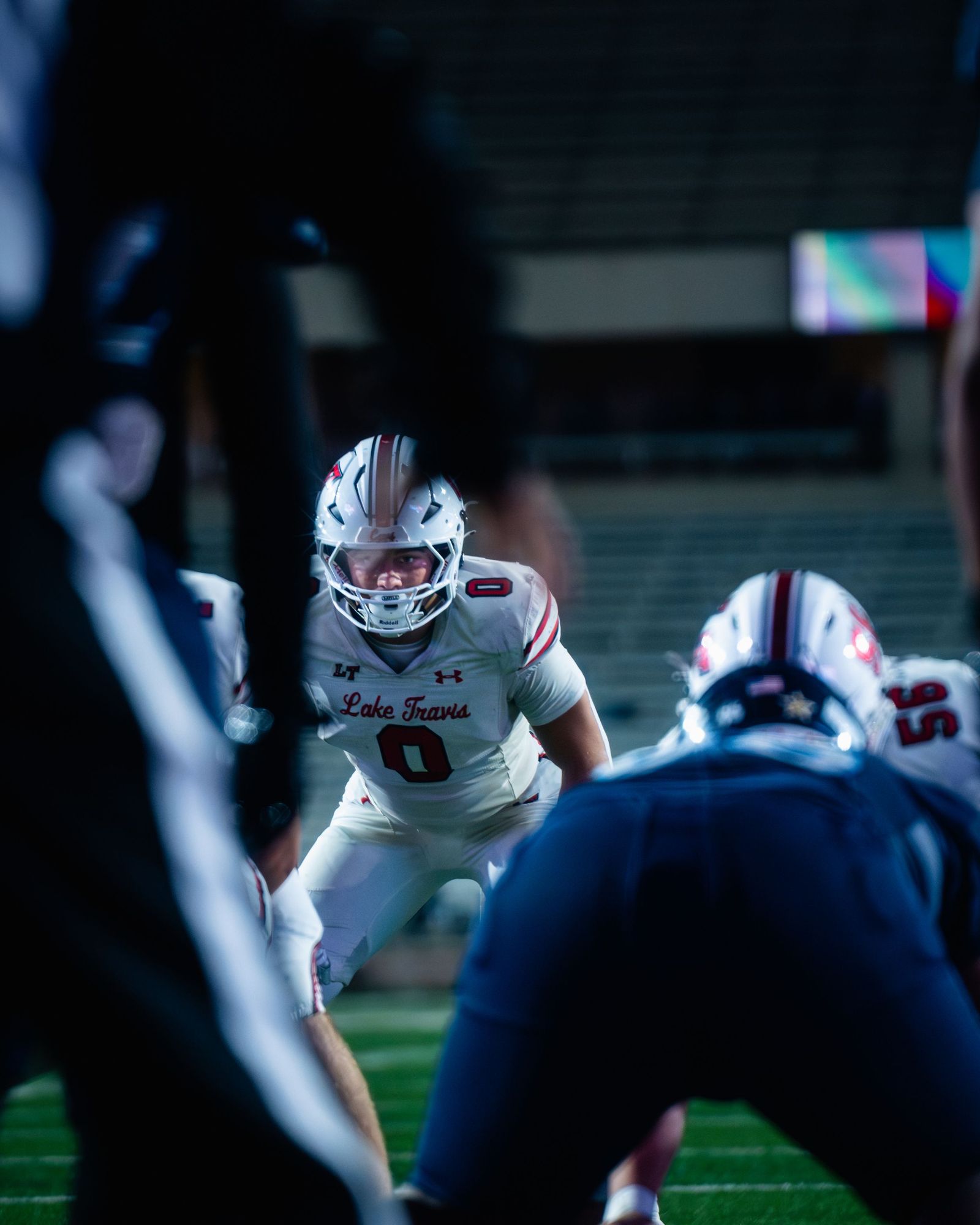 Football linemen set at the line of scrimmage under blue light