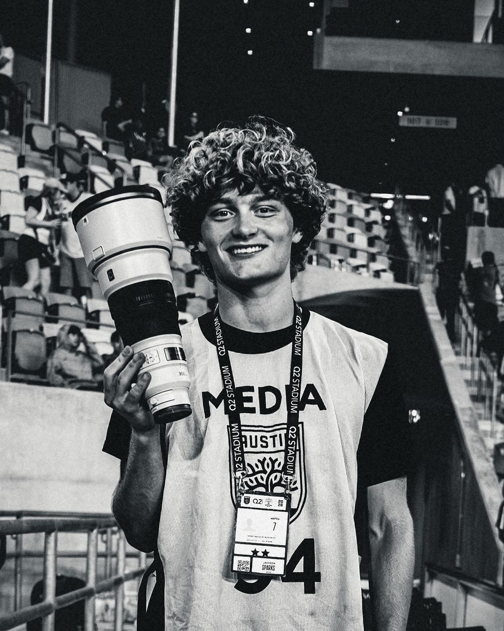 Jackson Sparks holding a telephoto lens in a media vest at Q2 Stadium